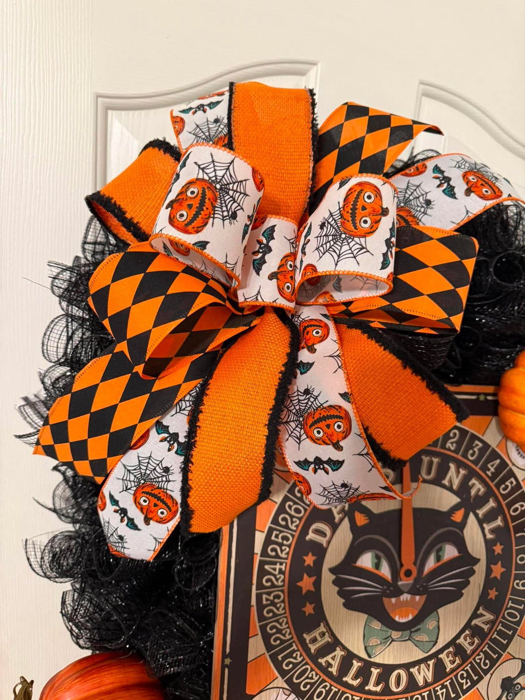 Halloween wreath bow detail - orange black harlequin and jack-o-lantern ribbon