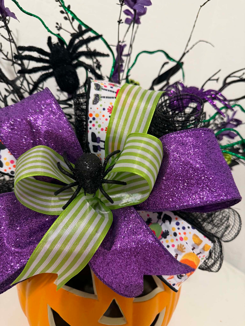 Close-up of purple glitter and lime green striped bow with spider accent