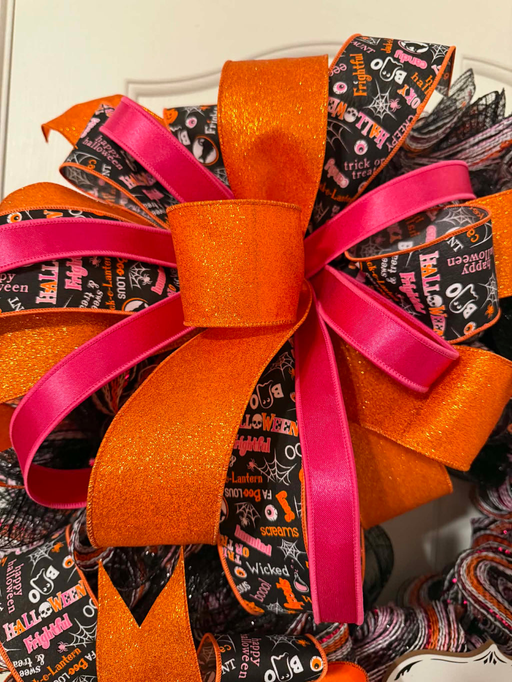 Close-up of layered orange glitter and hot pink bow on Halloween wreath