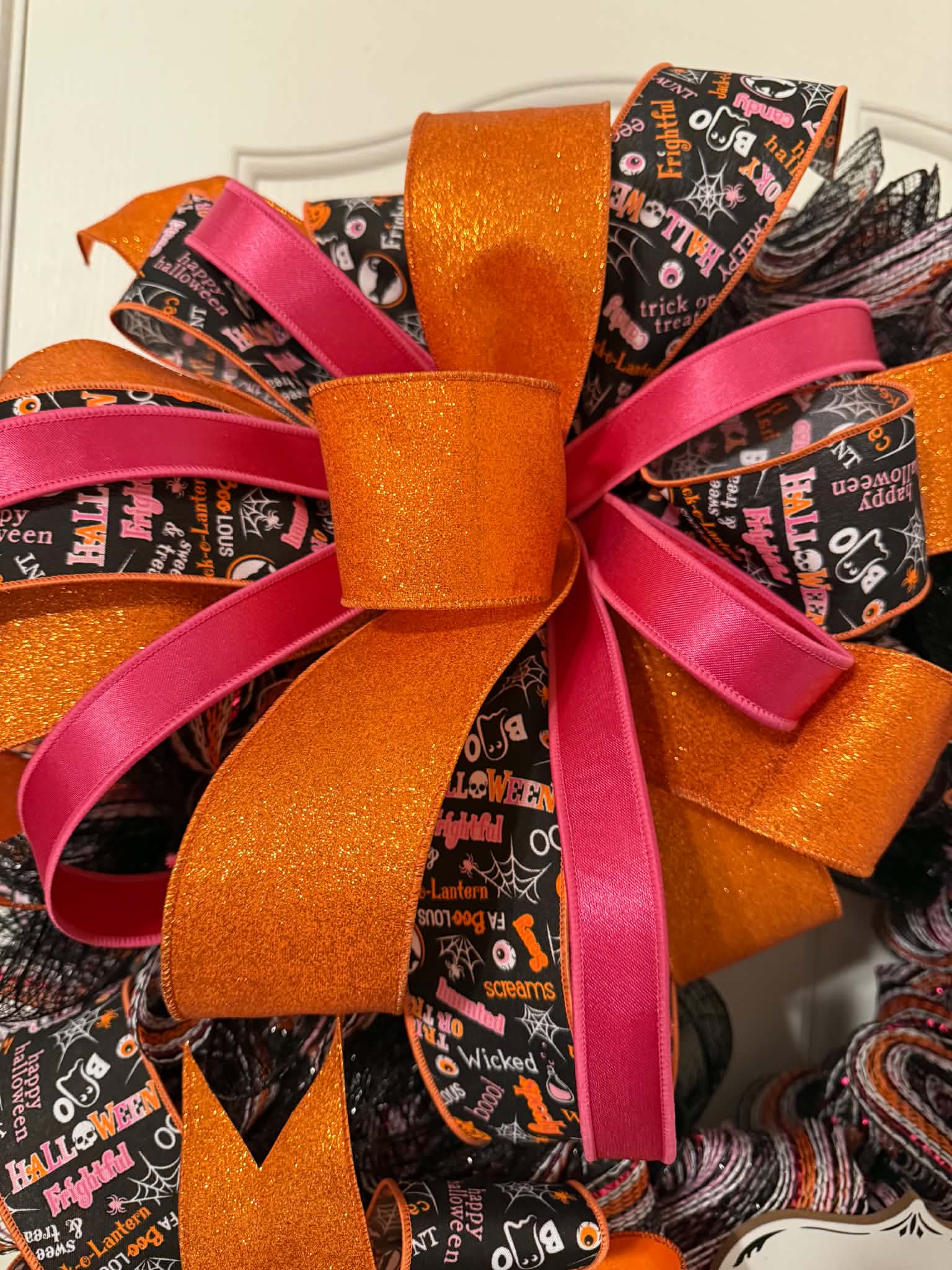 Close-up of layered orange glitter and hot pink bow on Halloween wreath