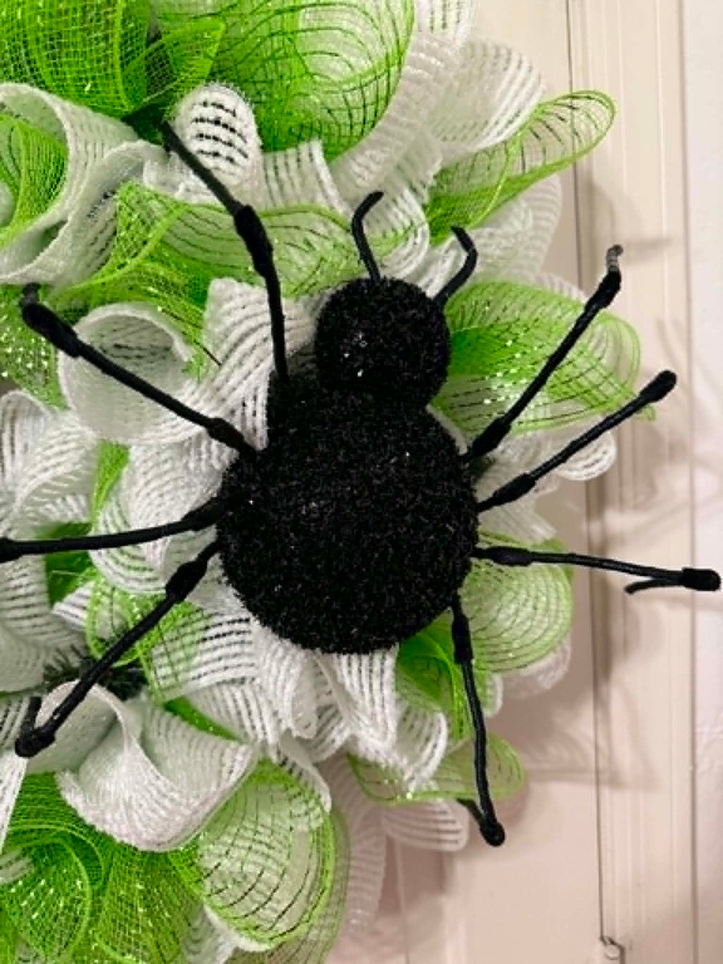 Close-up of black glitter spider centerpiece on lime green and white deco mesh wreath