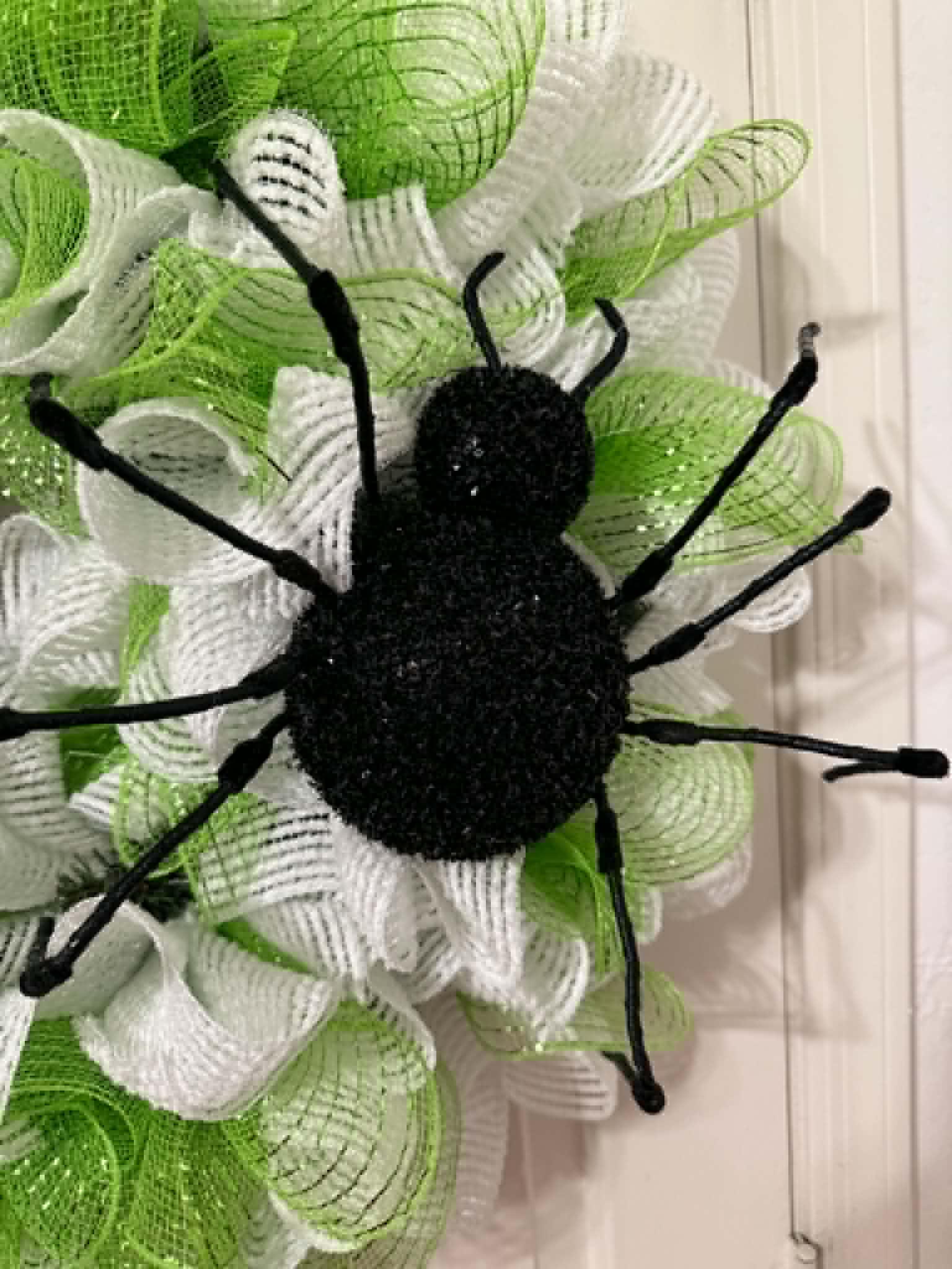 Close-up of black glitter spider centerpiece on lime green and white deco mesh wreath